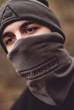 Angled view of Model wearing Grey snood with black OUT HOUSE! lettering and accompanying grey beanie to match 